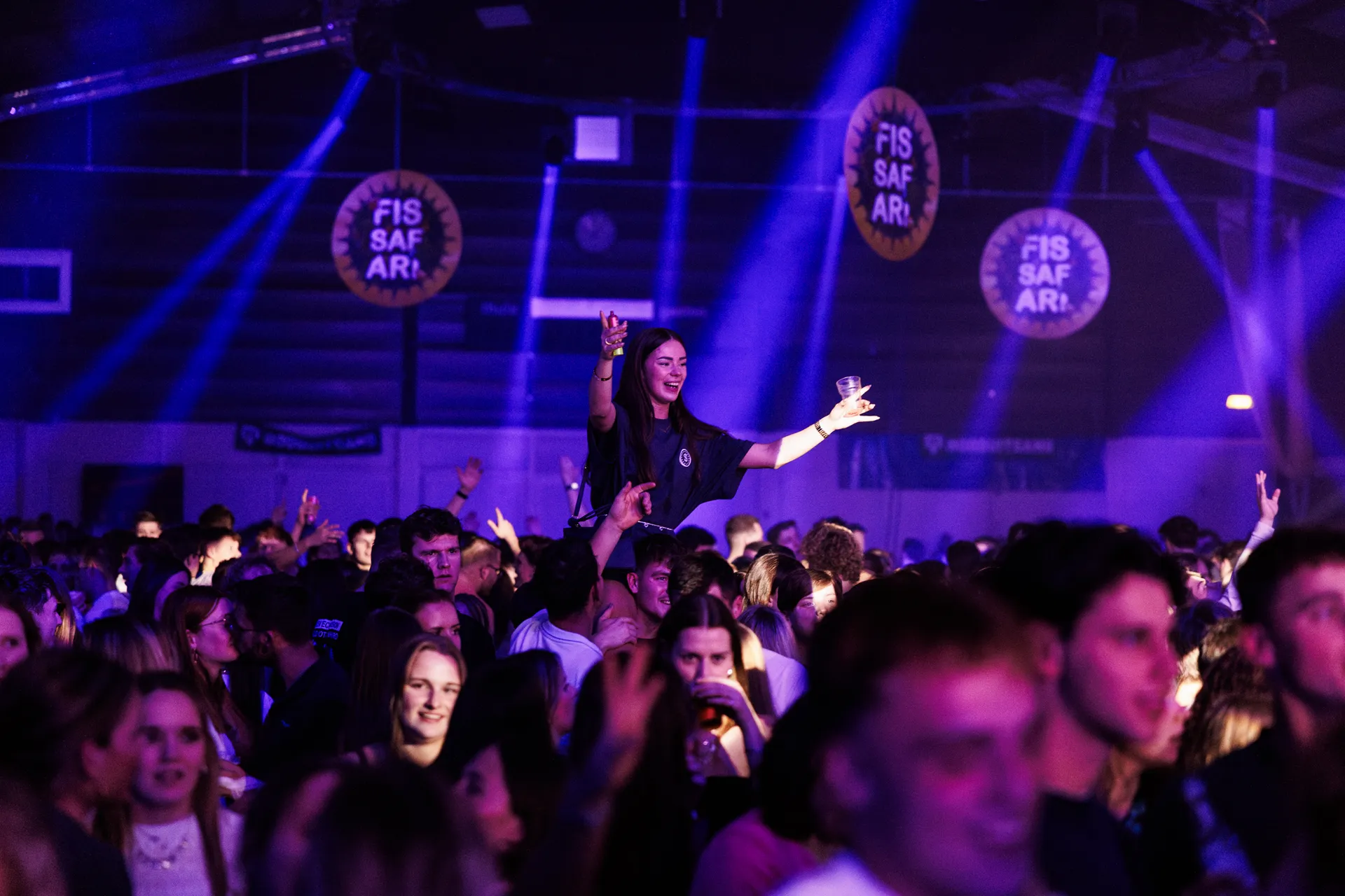 Publiek in blauw licht met Fissafari-logo's aan het plafond